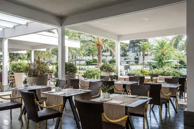 a restaurant with tables and chairs and palm trees at Ergife Palace Hotel in Rome