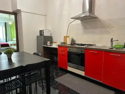 a kitchen with red cabinets and a stove and a table at Kobe's Apartment in Rome