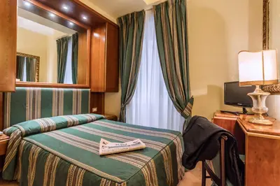 a hotel room with a bed and a mirror at Raeli Hotel Regio in Rome