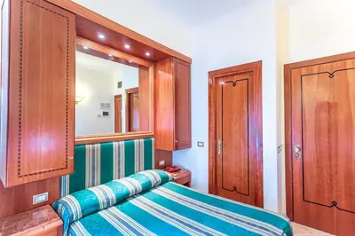 a bedroom with a bed with a mirror and wooden cabinets at Raeli Hotel Archimede in Rome