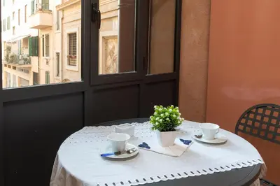 a table with a white table cloth and cups and a window at Dimora storica Palazzo Marescalchi Belli in Rome