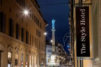 a street at night with a blue statue on a pole at The Style in Rome