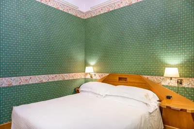 a bedroom with green wallpaper and a bed with white pillows at Hotel S. Anna in Rome