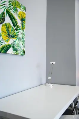 a white table in a room with a painting of palm trees at Enjoy Porta Furba in Rome