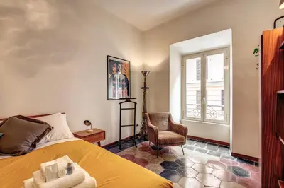 a bedroom with a bed and a chair and a window at Trastevere San Cosimato vintage in Rome