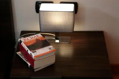 a stack of books sitting on a table next to a lamp at Residenza Delle Arti in Rome