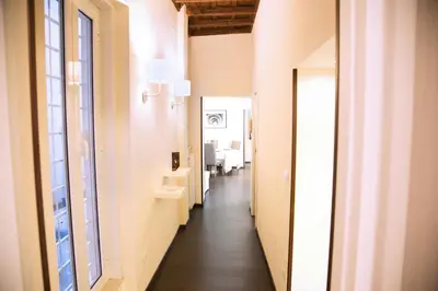 a corridor of an apartment with white walls and wood floors at H-Aviva Giubbonari Apartment in Rome