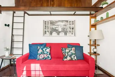 a red couch with blue pillows in a living room at Trastevere Alley Apartment in Rome