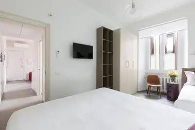 a white bedroom with a large bed and a chair at ROMAC Villa Borghese with 3 bedrooms near Via Veneto in Rome