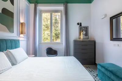 a bedroom with a bed and a chair and a window at ROMAC Mazzini with 5 bedrooms near the Vatican in Rome