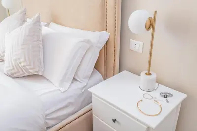 a white bed with white pillows and a lamp on a night stand at Daplace - La Mongolfiera Rooms in Navona in Rome