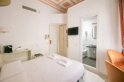 a white room with a bed and a bathroom at Caffe' e Cuscino in Rome