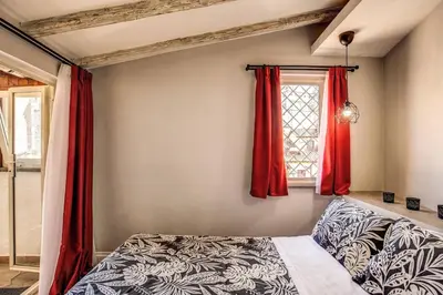 a bedroom with red curtains and a bed and a window at Attic with Terrace by Trevi Fountain in Rome