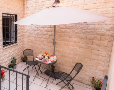 a table with chairs and an umbrella on a patio at Leonina 75 Holidays in Rome