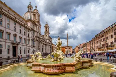 a fountain in the middle of a street with buildings at Antica dimora navona in Rome
