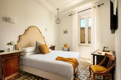 a bedroom with a bed and a desk and a window at Guesthouse Serafino in Rome