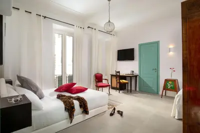 a bedroom with a white bed with red pillows and a desk at Guesthouse Serafino in Rome