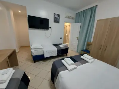 a hotel room with two beds and a flat screen tv at Hotel Positano in Rome
