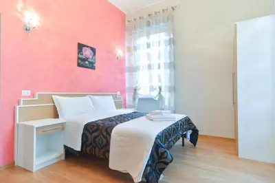 a bedroom with a bed and a pink wall at Trani B&T Rooms in Rome