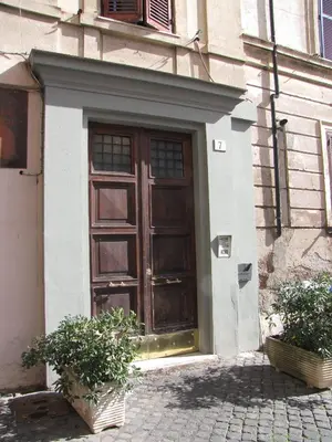a large wooden door on a building with two plants at Trastevere Colors in Rome