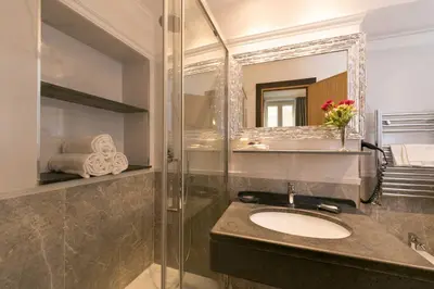 a bathroom with a sink and a shower with a mirror at DK Suites in Rome