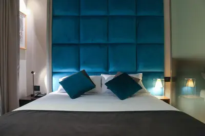 a bedroom with a large bed with a blue headboard at Triviho Hotel in Rome