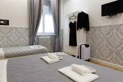 a bedroom with two beds and a dress hanging in a window at Domus St. John in Rome