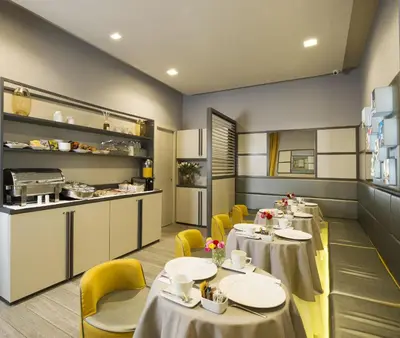 a restaurant with tables and yellow chairs and a kitchen at San Carlo Suite in Rome