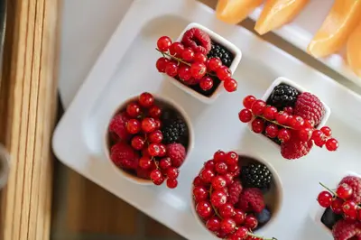 a white plate with berries and fruits in bowls at Portrait Roma - Lungarno Collection in Rome