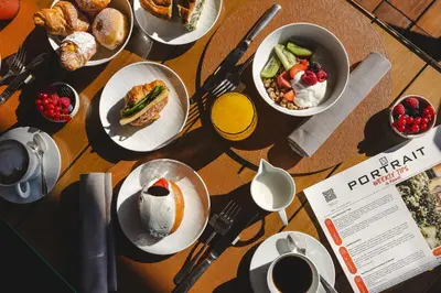 a table topped with plates of breakfast foods and coffee at Portrait Roma - Lungarno Collection in Rome