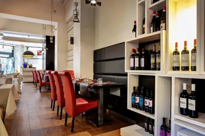 a restaurant with a bar with red chairs and bottles of wine at Dharma Luxury Hotel & SPA in Rome