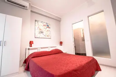 a white bedroom with a red bed and a window at The Colours Of Rome in Rome