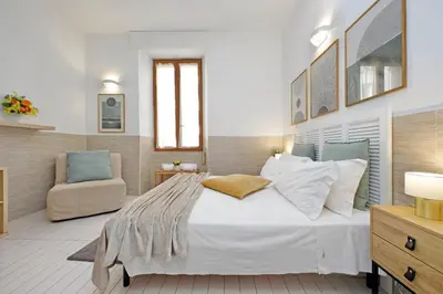 a bedroom with a large white bed and a chair at Opera Inn Suites - Rooms and Apartments in Rome
