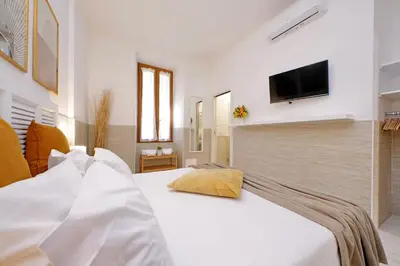 a bedroom with a white bed with a television on the wall at Opera Inn Suites - Rooms and Apartments in Rome