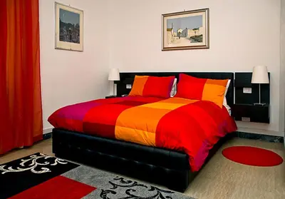 a bedroom with a colorful bed with red and orange pillows at Vatican Paradise in Rome