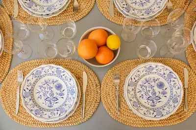 a table with plates and utensils and a bowl of oranges at ROMAC Condotti with 3 bedrooms near the Spanish Steps in Rome
