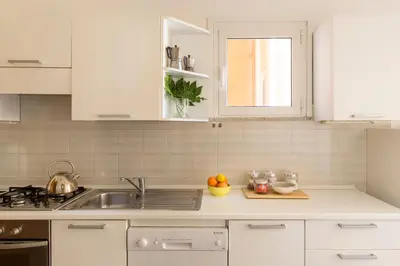 a white kitchen with a sink and a counter top at ROMAC Condotti with 3 bedrooms near the Spanish Steps in Rome