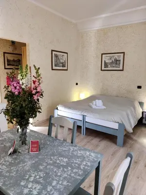 a bedroom with a bed and a table with a vase of flowers at St. Peter's Rooms Rome in Rome