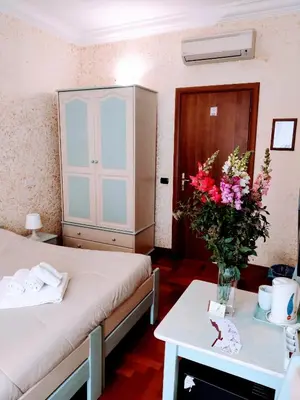 a room with two beds and a table with flowers at St. Peter's Rooms Rome in Rome