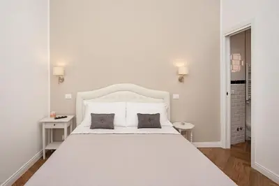 a white bedroom with a large white bed with two pillows at Luxury & Charme Colosseo in Rome
