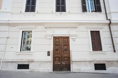 a white building with a wooden door and two windows at Luxury & Charme Colosseo in Rome