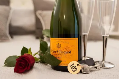 a bottle of wine on a table with a rose and keys at Lifestyle Veneto Suite in Rome