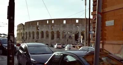 a city street with cars parked in front of a building at Nvmen Apartment con Terrazza al Colosseo in Rome