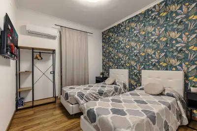 two beds in a room with floral wallpaper at Nvmen Apartment con Terrazza al Colosseo in Rome