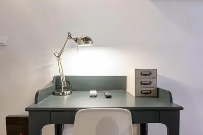 a desk with a lamp and a white chair at Monserrato Apartment in Rome