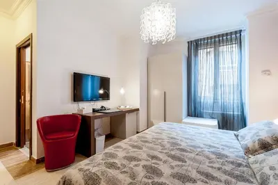 a bedroom with a bed and a desk and a television at La Dolce Vita Barberini in Rome