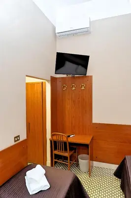 a room with a desk and a bed and a table at Hotel Cervia in Rome