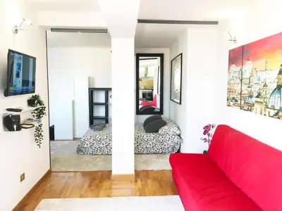 a living room with a red couch and a bed at Appartamento con magnifico terrazzo vicino a Metropolitana e Vaticano in Rome