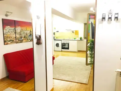 a living room with a red couch and a kitchen at Appartamento con magnifico terrazzo vicino a Metropolitana e Vaticano in Rome