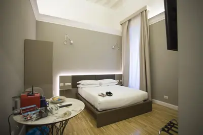 a small bedroom with a bed and a table at Ripetta 25 Prestige Rooms in Rome